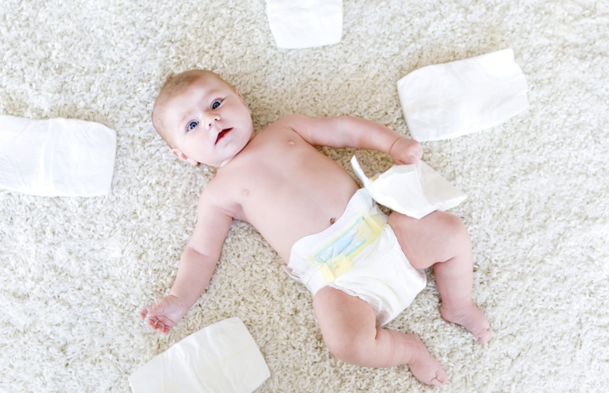 baby surrounded by diapers