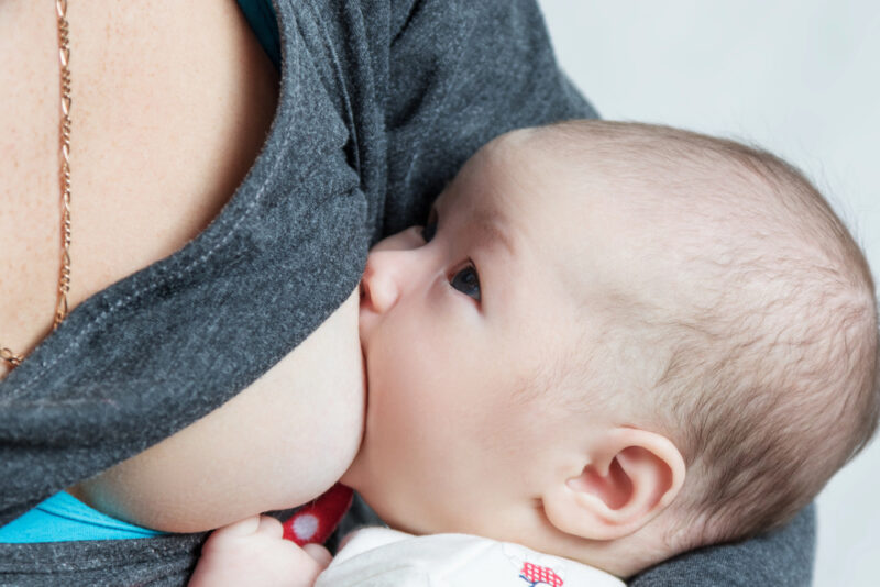 Newborn nursing at mother's bare breast