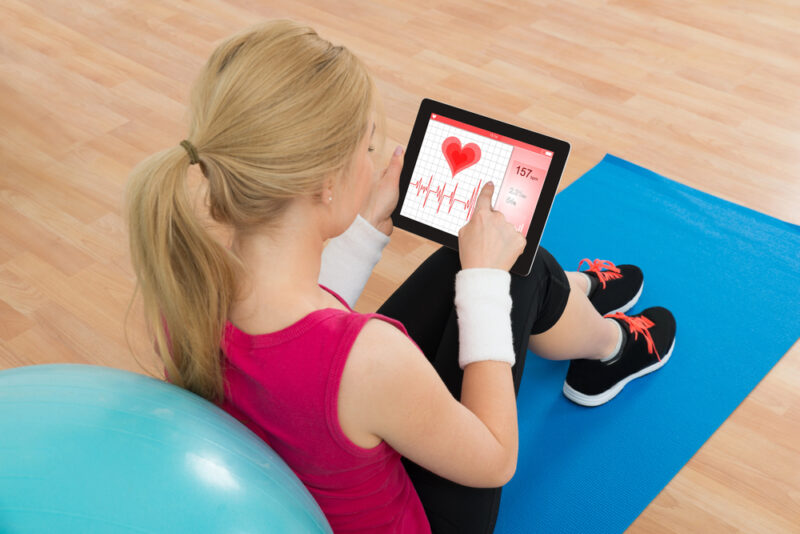 Woman on exercise mat checking heart rate